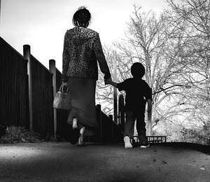 Rear view of father and daughter walking on bare tree