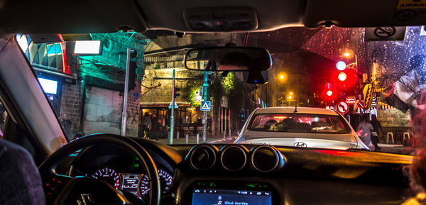 Vehicles on road in city seen through car windshield at night