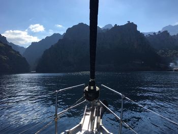 Sailboat sailing on sea by mountains against sky