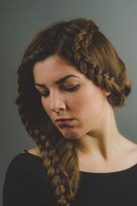 Portrait of young woman looking away against gray background