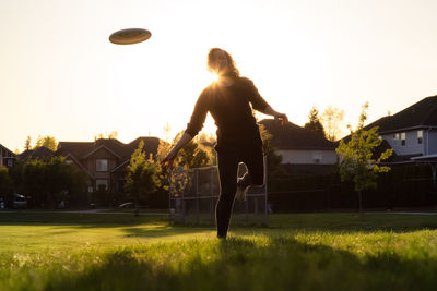 Woman playing with ball against sky during sunset