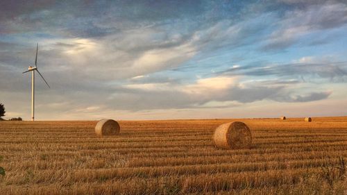 Hay bales on field against sky