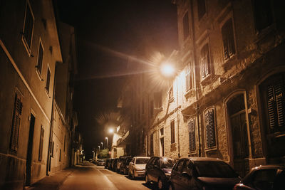 Street amidst illuminated buildings in city at night