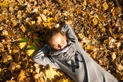 High angle view of girl lying down on leaves during autumn