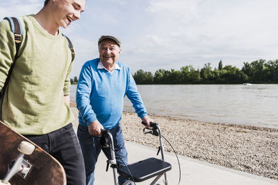 Grandfather and grandson strolling together at riverside