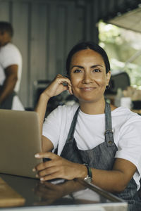 Portrait of smiling female seller with laptop in food truck