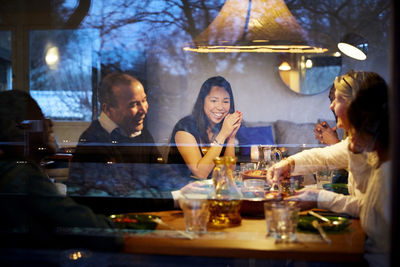 Multi-generation family enjoying dinner at table seen through glass window