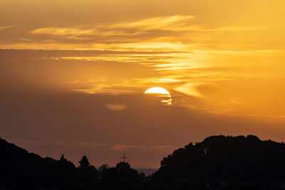 Scenic view of silhouette landscape against orange sky