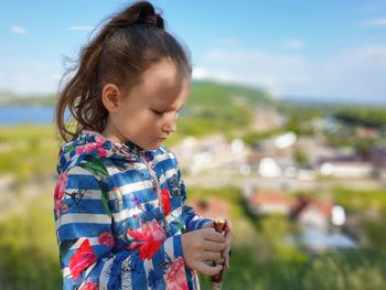 Portrait of a girl looking at her hands against village view