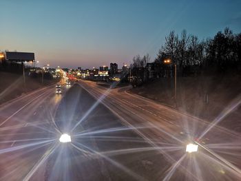 Illuminated street against sky at night