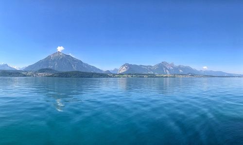 Scenic view of sea and mountains against clear blue sky