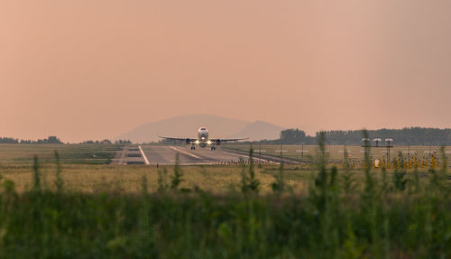 Airplane landing against clear sky during sunset