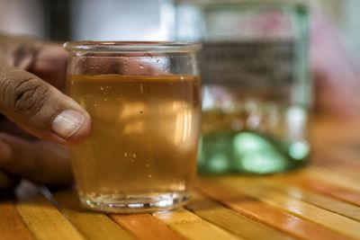Close-up of hand holding wine glass on table
