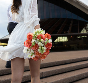Low section of woman standing by white rose