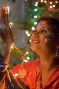 Smiling woman holding string light at night