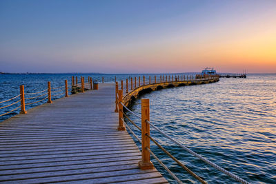 Pier over sea against clear sky during sunset