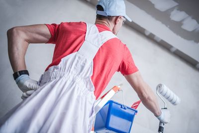 Rear view of man holding paint roller at home