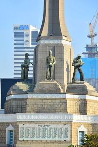 Statue in city against sky