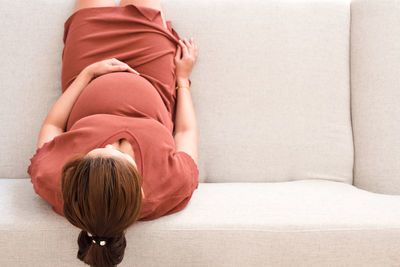 Directly above shot of pregnant woman sitting on sofa at home