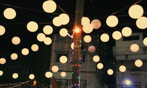 Low angle view of illuminated light bulbs hanging from ceiling
