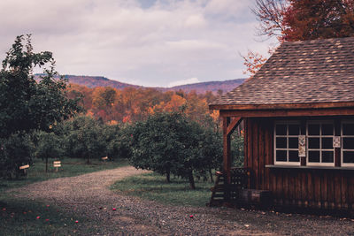 Trees by house against sky during autumn