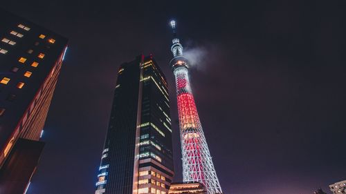 Low angle view of illuminated buildings against sky at night