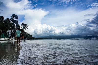 Rear view of man in sea against sky