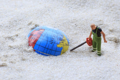 Figurine and globe on sand at beach