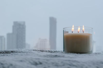 Flames burning at blurred aroma candle puts near by window in winter season. zen and relax concept.