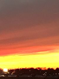 Silhouette city against dramatic sky during sunset