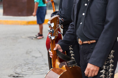 Midsection of men with string instruments on street