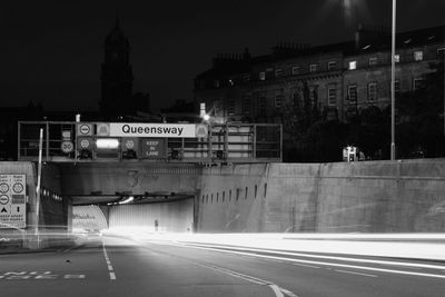 Light trails on street leading towards tunnel in city at night