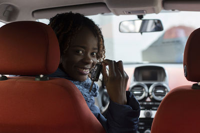 Portrait of smiling woman holding car key sitting in car