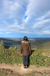 Rear view of woman standing on field against sky