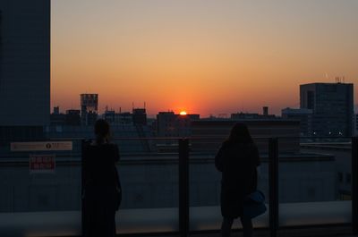 Silhouette of woman standing at sunset