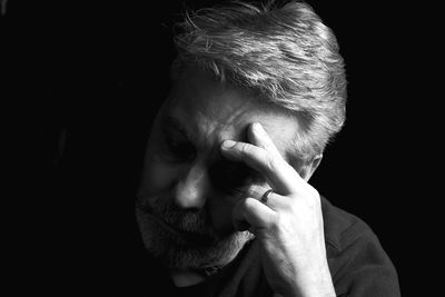 Close-up of man with hand against black background