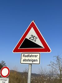 Low angle view of road sign against clear blue sky