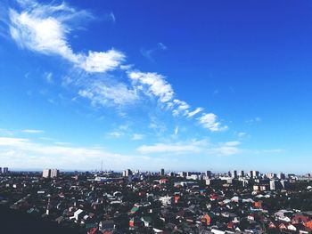 Aerial view of city buildings against blue sky