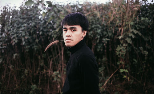 Portrait of young man standing in forest