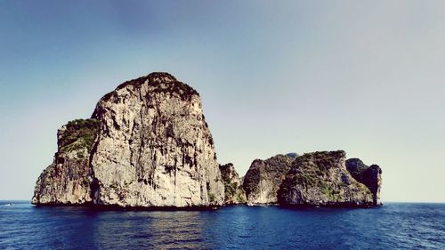 Rock formations in sea against clear sky