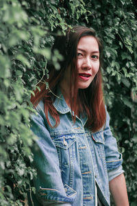 Portrait of smiling young woman standing against plants