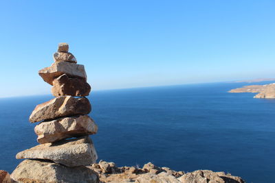 Stack of rocks by sea against sky