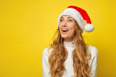 Portrait of a smiling young woman against yellow background