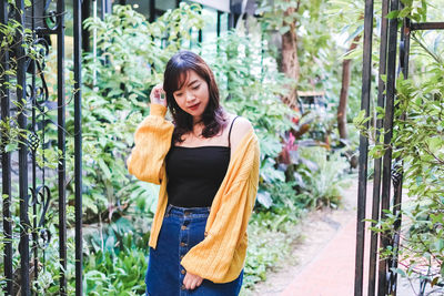 Portrait of smiling young woman standing against plants