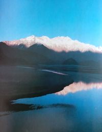 Scenic view of sea and mountains against blue sky