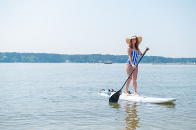 Young woman in lake against sky