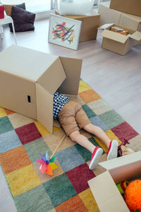 Low section of boy in cardboard box on carpet at home