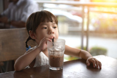 Portrait of boy drinking water from glass on table