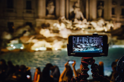 Fountain in front of historical building reflecting in mobile phone