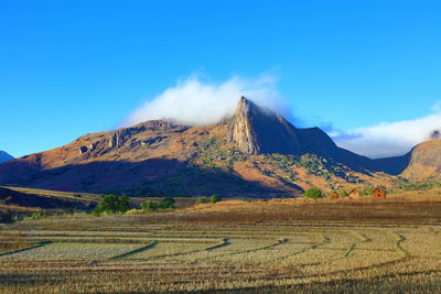 Scenic view of field and mountains against blue sky